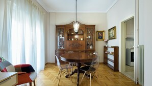 Ein Esszimmer mit einem Holztisch, transparenten Stühlen, einer Chandelier und einer Holztruhe mit Glastüren.