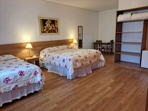 A hotel room with two beds, wooden headboards, a wooden wardrobe, a desk, and a chair. - Pousada Recanto Feliz (Campos do Jordão)