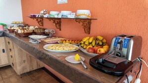 Un mostrador de buffet amb diferents plats, una torradora i una escudella de fruita.
