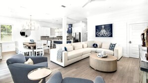 A spacious living area with a large L-shaped sofa, a round coffee table, and a striped armchair. - Vista! Ocean Views from rooftop deck! (Destin)