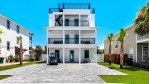 A multi-story residential building with a central entrance, balconies, and a paved driveway. - Vista! Ocean Views from rooftop deck! (Destin)