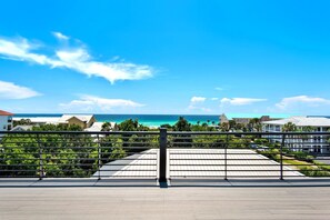 A coastal view with a clear sky, a metal railing, and buildings in the background.