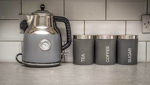 A kitchen with a coffee maker, a kettle, and three labeled containers for tea, coffee, and sugar. - Two Bedroom Apartment, Sleep 5, Old Swan (Old Swan)