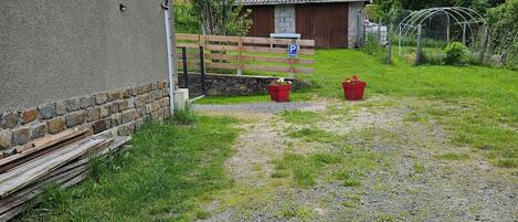A gravel path leading to a wooden fence and a building with a stone wall.