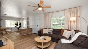Ein modernes Wohnzimmer mit einem braunen Sofa, einem Holztisch und einem Deckenventilator.