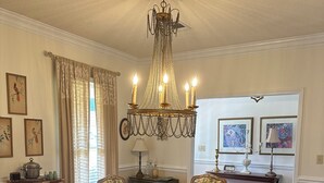 A dining room with a large wooden table surrounded by upholstered chairs, a chandelier, and framed artwork on the walls. - Foot ball game weekends and events (Oxford)