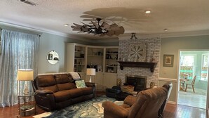 A living room with a fireplace, leather sofas, a ceiling fan, and a bookshelf. - Foot ball game weekends and events (Oxford)