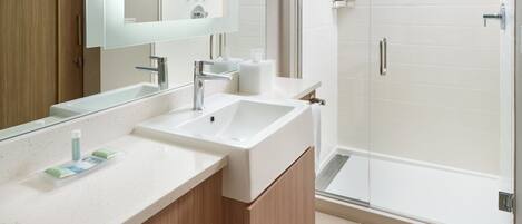 A modern bathroom with a large mirror, two sinks, and a glass shower enclosure.