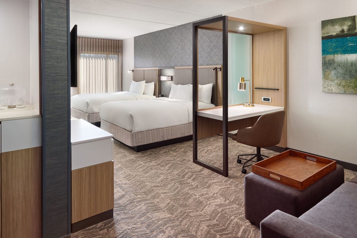 A modern hotel room with a large bed, a desk, and a seating area.