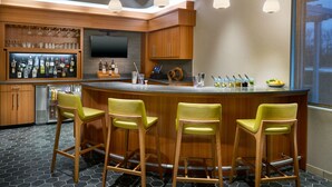 A modern kitchen with a bar area, wooden cabinets, bar stools, and a large screen TV. - SpringHill Suites by Marriott Arlington TN (Arlington)