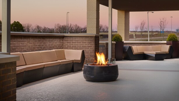 An outdoor seating area with a fire pit, brick walls, and a covered section. - SpringHill Suites by Marriott Arlington TN (Arlington)