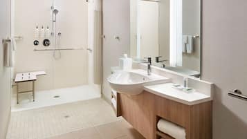 Un bagno moderno con doccia a filo pavimento, due lavandini, un mobile vanitario e uno specchio grande.