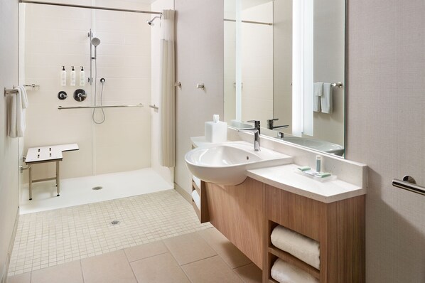 Un baño moderno con ducha a ras de suelo, dos lavamanos, tocador y un espejo grande.