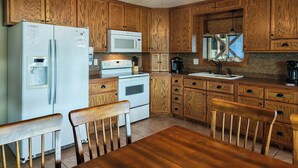 A kitchen with wooden cabinets, a refrigerator, a microwave, a stove, and a ceiling fan.