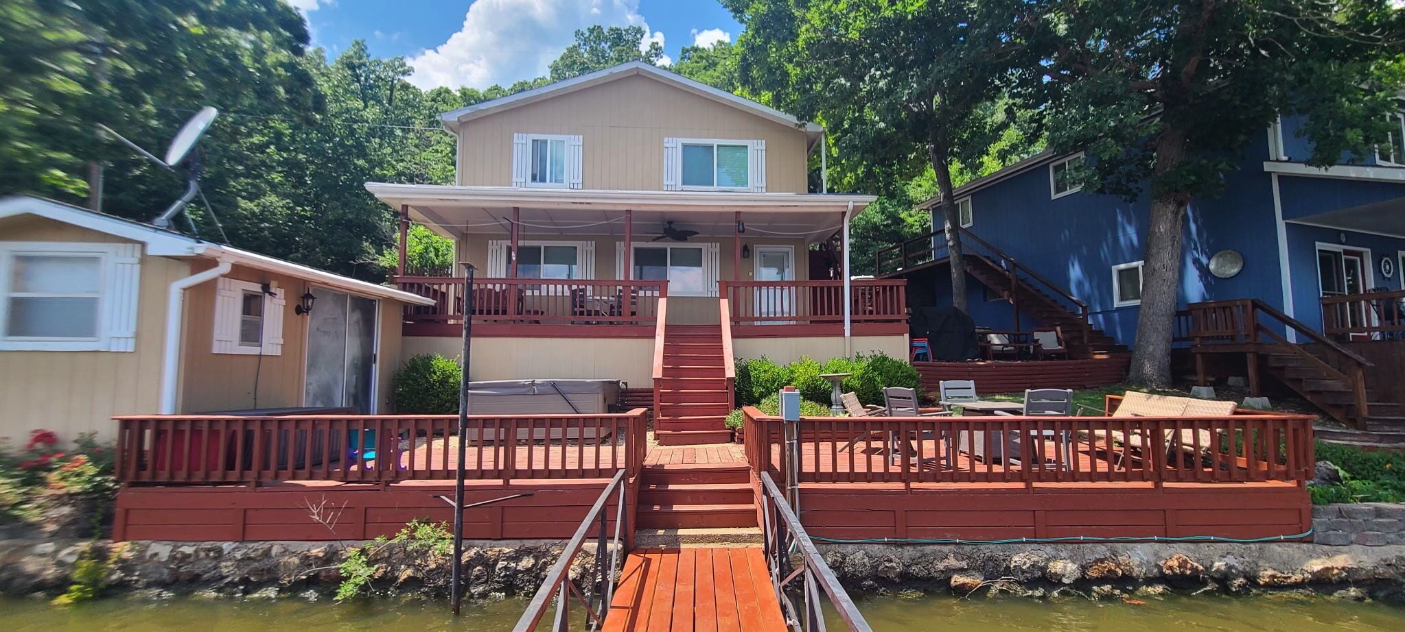 A two-story house with a wooden deck and a staircase leading to the upper floor.