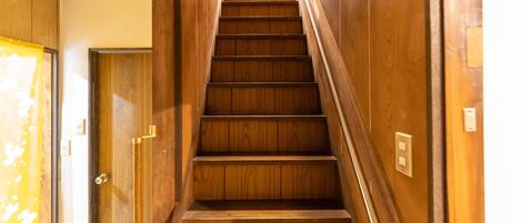 Una escalera de madera con barandilla que da acceso a un ascensor.
