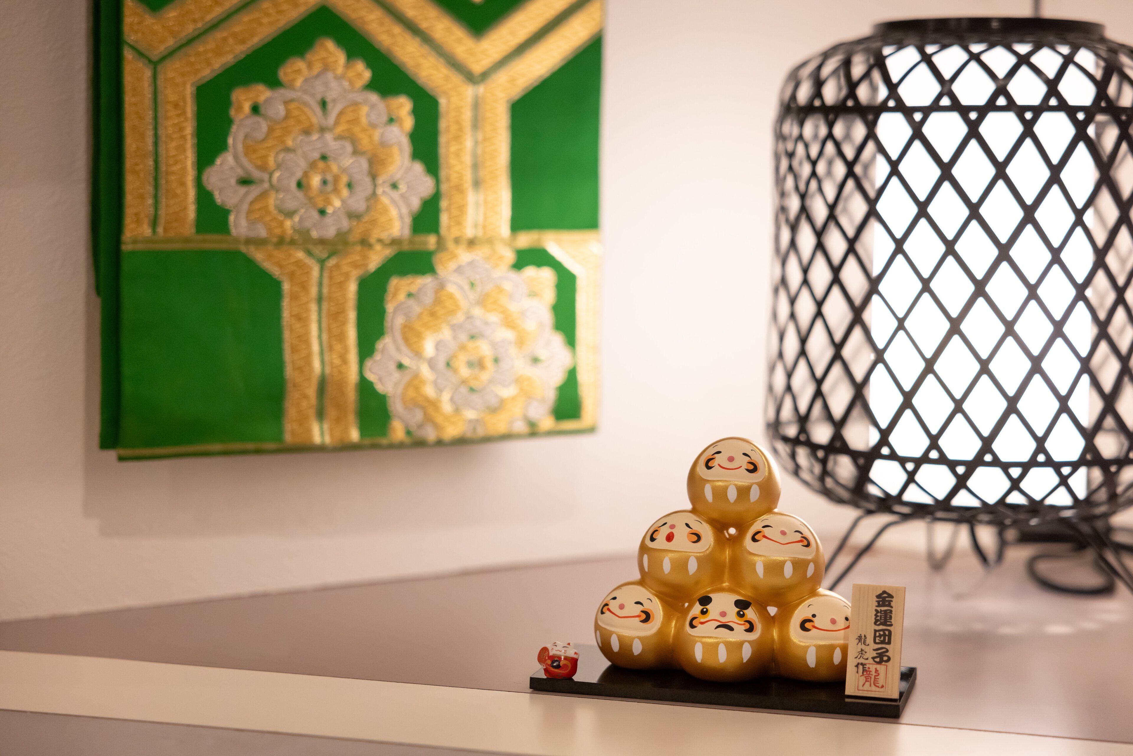 Une composition décorative composée d’objets sphériques ornés de visages, disposés sur une table, ainsi qu’une petite figurine et une œuvre d’art encadrée accrochée au mur.