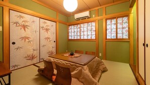 A traditional Japanese room with tatami flooring, a low table with a tea set, sliding shoji doors, and a view through a window with a floral pattern. - Karakara (Osaka)