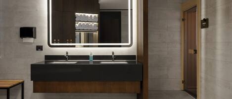 Un baño moderno con un espejo grande, dos lavamanos y un banco de madera.