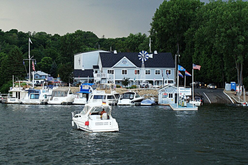 A marina with several boats docked, a windmill, and a building with a sign that reads "Windmill Marina."
