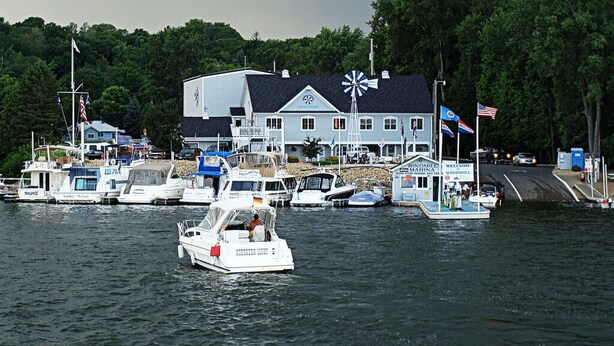 En småbåtshamn med flera båtar förtöjda, ett vindkraftverk och en byggnad med en skylt som lyder: ”Vindkraftverkshamnen”.