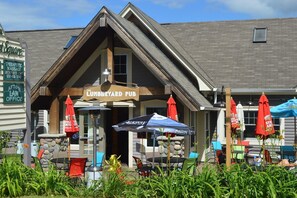 A building with a sign reading "The Lumberyard Pub" and outdoor seating with umbrellas. - Modern Suite in Downtown Afton, 5min to skiing, hiking, riverboating & more! (Afton)