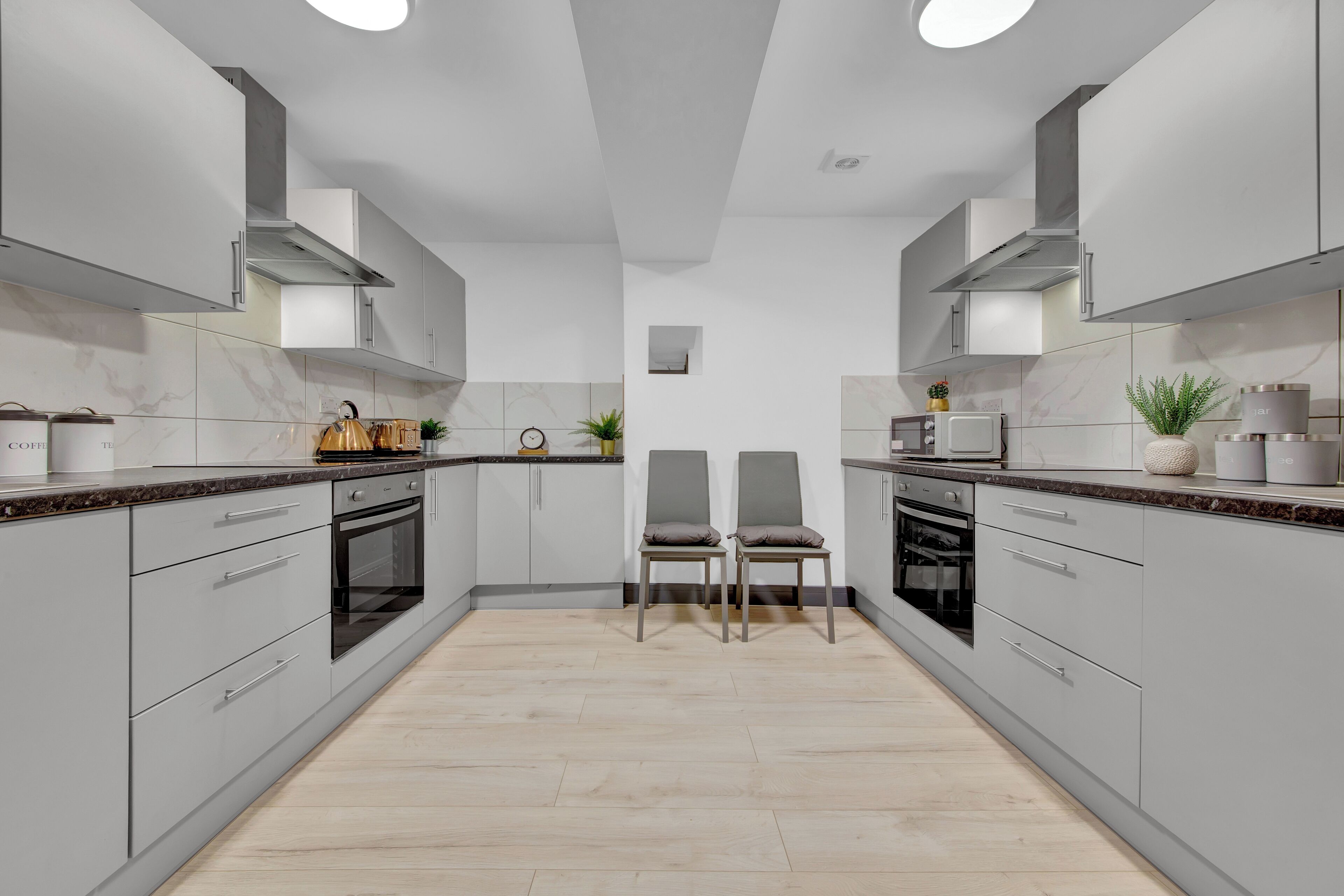 Una cocina moderna con gabinetes grises, una isla central y dos sillas.