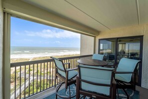 Enjoy ocean views from this balcony with two chairs and a table.