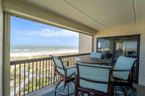 Enjoy ocean views from this balcony with two chairs and a table.