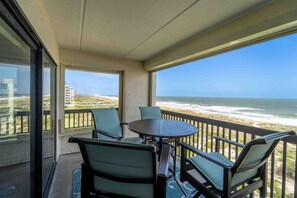 Enjoy the ocean view from this balcony with a round table and four chairs.