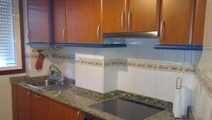 Eine Küche mit Holzausstattung, einem Edelstahlspülbecken, einem Einbauofen und einer Arbeitsplatte aus Granit.
