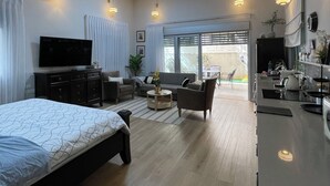 Una habitación de hotel moderna con cama, sofá, zona de comedor y un gran ventanal.