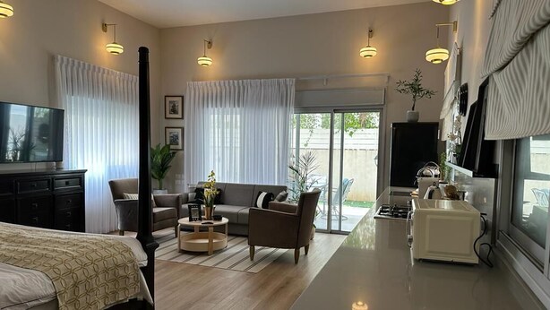 Una habitación de hotel moderna con cama, sofá, zona de comedor y cocina.