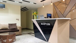 Een receptiebalie met een modern design, een bank en een decoratieve vaas met zonnebloemen.
