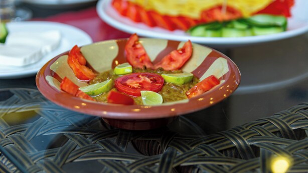 Une table à manger avec un saladier et d’autres plats.