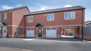 A two-story brick building with a central entrance, two garages, and a small attached structure with a sloped roof. - Butterfly Gardens (Woodville)