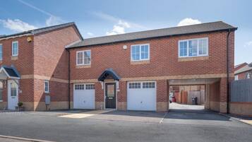 A two-story brick building with a central entrance, two garages, and a small attached structure with a sloped roof.