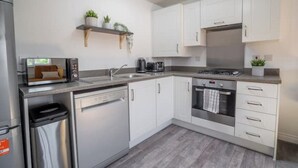 A modern kitchen with white cabinets, stainless steel appliances, and a built-in oven. - Butterfly Gardens (Woodville)