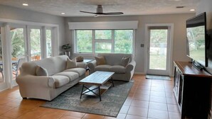 A spacious living room with a white sofa, a coffee table, and a ceiling fan. - Boater’s Paradise: 3BR Canal Front Home + Fish Cleaning Station (Big Pine Key)
