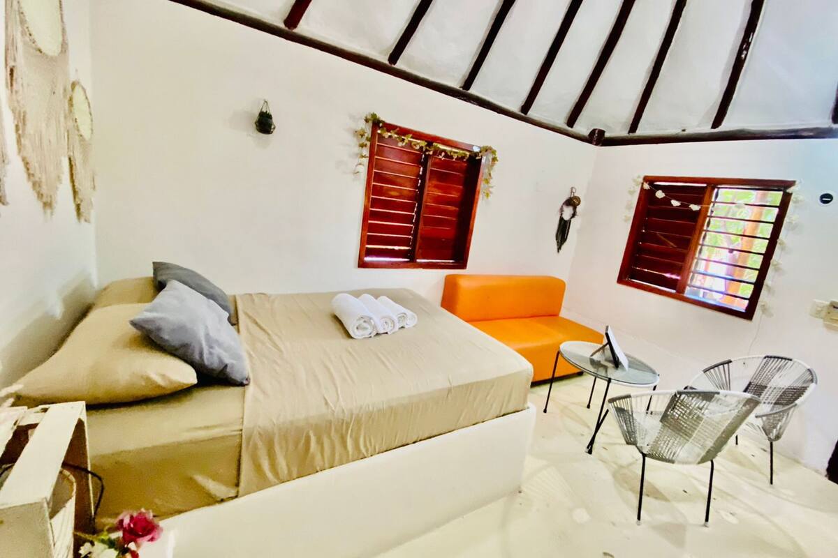 Une pièce comprenant un lit, un canapé orange, une petite table et deux chaises.