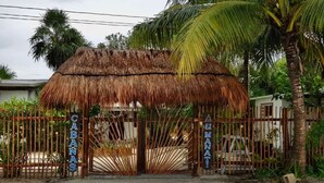 A thatched-roof structure with a bamboo fence and signs reading "CABANAS" and "EL MANATI". - Cabañas Manati (Isla Holbox)