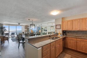 Una cocina con armarios de madera, encimeras de granito y vistas al exterior.