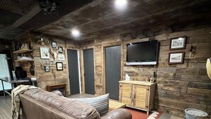 Un salon chaleureux avec un canapé en cuir marron, un meuble en bois et un téléviseur fixé au mur.