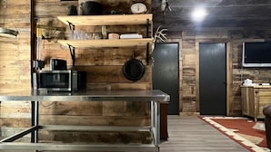 Une cuisine rustique avec des étagères en bois, un four à micro-ondes, une balance et un réfrigérateur.