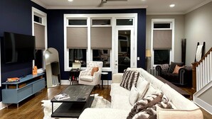 A living room with a sofa, coffee table, TV, and a ceiling fan. - MusikHouse East I Rooftop + Hot Tub I 5 mi to DWNT (Nashville)