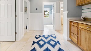 A hallway with a patterned rug, wooden cabinets, and a view to a balcony. - Captiva Home New to Rental Market ! (Captiva)