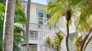 A two-story building with a white exterior and green accents, surrounded by palm trees. - Captiva Home New to Rental Market ! (Captiva)