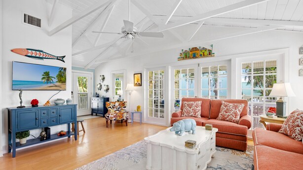A spacious living room with a white ceiling fan, a large TV, and a red sofa. - Captiva Home New to Rental Market ! (Captiva)