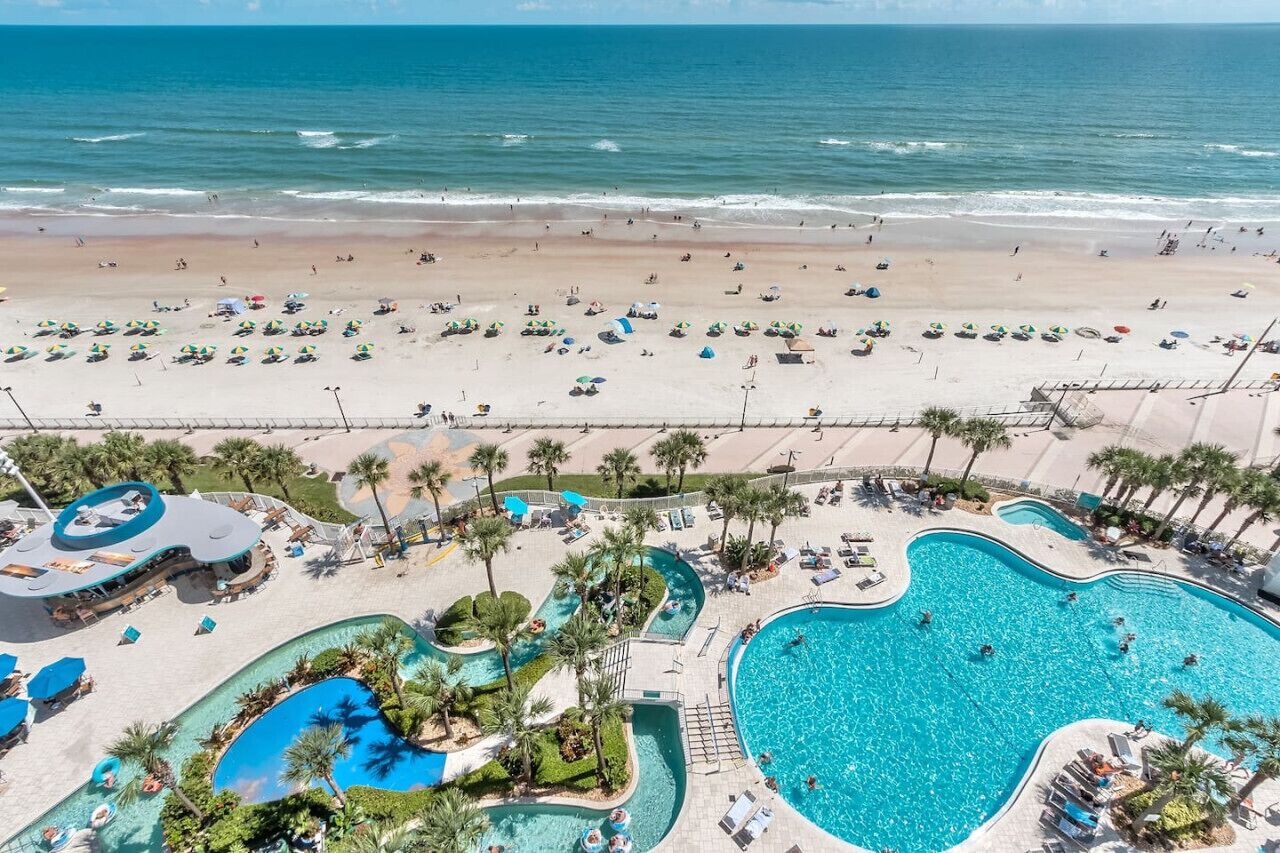 A resort with a large pool area, a beach, and a water slide.