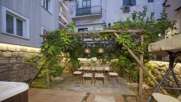An outdoor patio with a wooden pergola, stone pathway, and a hot tub. - Appartamento Terrazza Tasso (Sorrento)